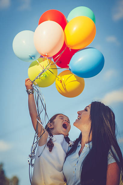 mutter und tochter mit luftballons - child balloon happiness cheerful stock-fotos und bilder