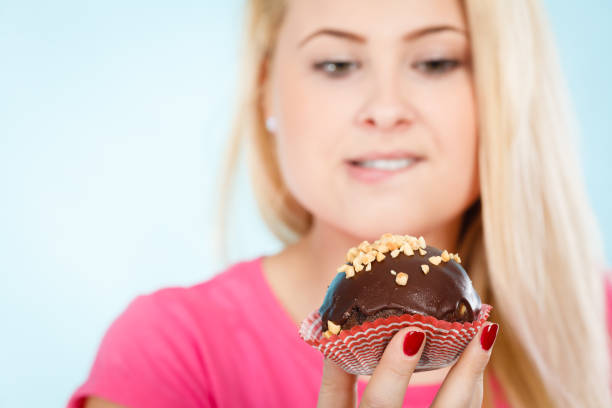 istock Woman holding chocolate cupcake about to bite 638931972
