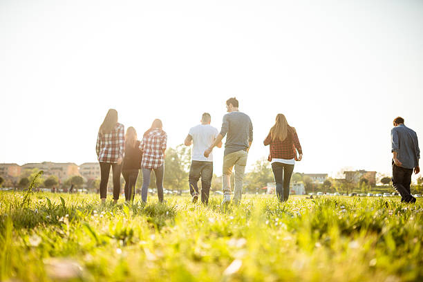 Group of people running on the park at dusk Group of people running on the park at dusk teenager adolescence campus group of people stock pictures, royalty-free photos & images