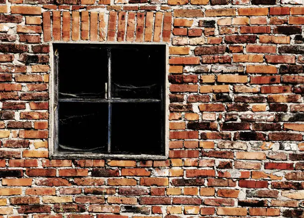 old brick wall with a broken square window
