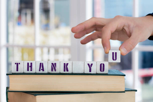 THANK YOU Concept , holding alphabet block with hand on closed book.Male Hand showing building blocks placed on the closed book