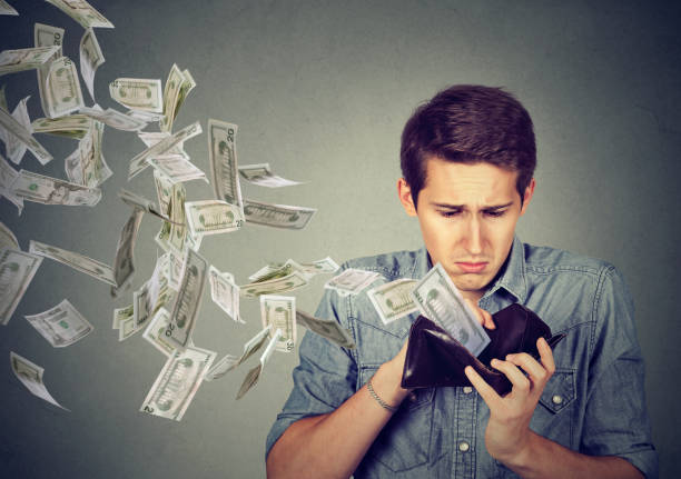 hombre mirando la billetera con dólares de dinero volando lejos - actividad comercial fotografías e imágenes de stock