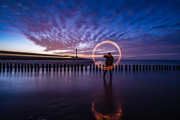 Person spinning fire on the beach at dusk in winter
