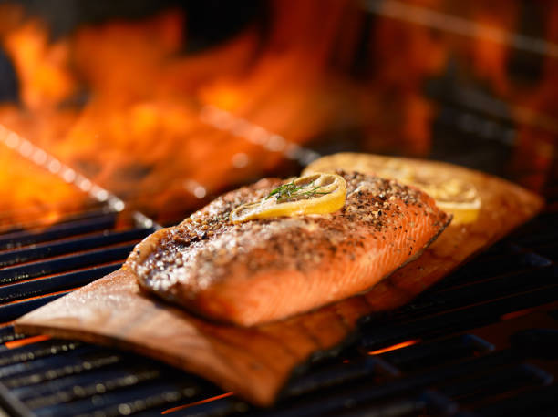 istock salmon cooking on cedar plank over open flame on  grill 638951206