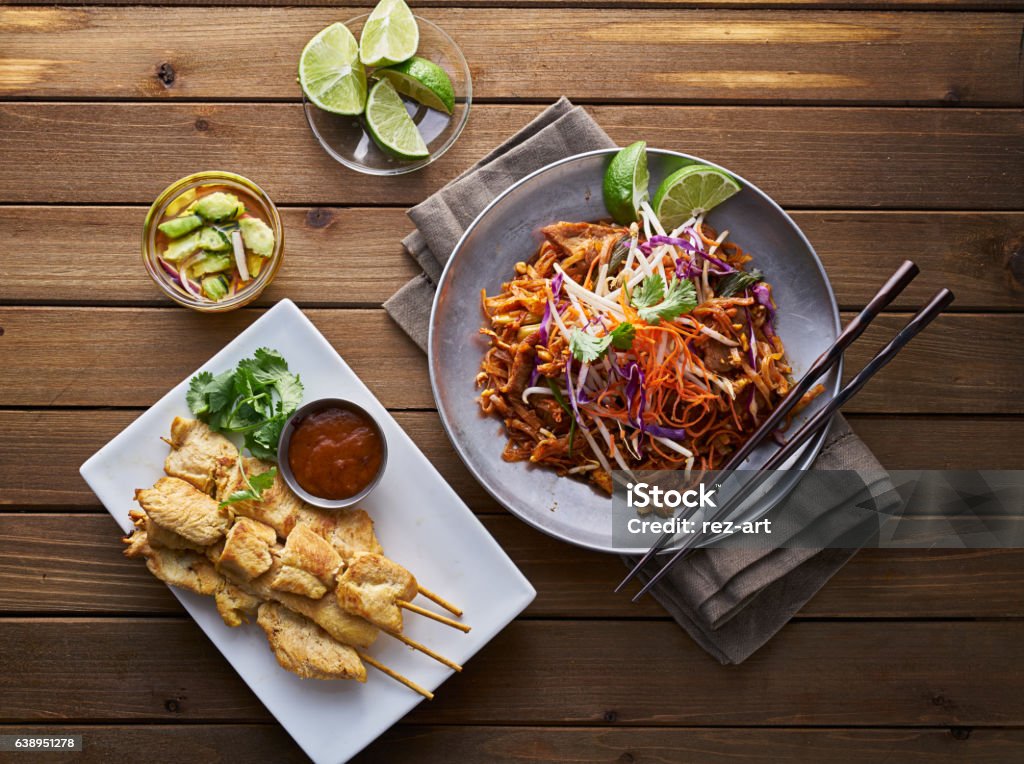 beef pad thai and chicken satay dinner viewed from above beef pad thai and chicken satay dinner viewed from above on wooden table Thai Food Stock Photo