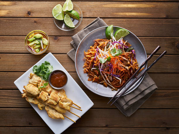 beef pad thai and chicken satay dinner viewed from above beef pad thai and chicken satay dinner viewed from above on wooden table thai food stock pictures, royalty-free photos & images