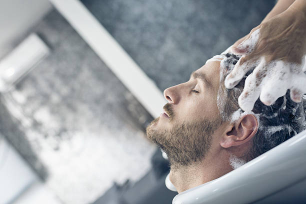 Young man getting his hair washed by a female hairdresser.