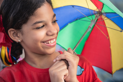 Smiling girl at carnival holding a colorful umbrella
