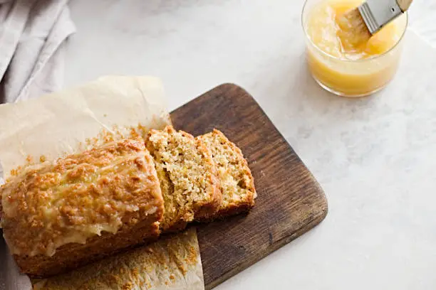 Glazed applesauce oatmeal bread on a white marble table. Ideal healthy breakfast with coffee and loaf cake.