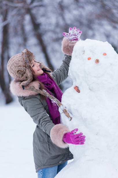 istock Young beautiful cheerful winter girl making snowman 638958462