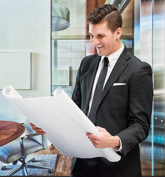 istock Smiling businessman holding blueprint in office 638959632