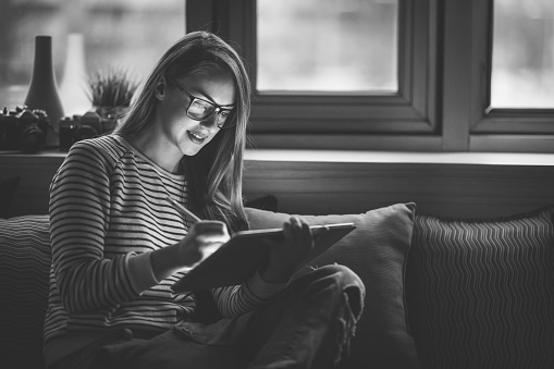 Young woman sitting on the sofa,relaxing and using digital tablet