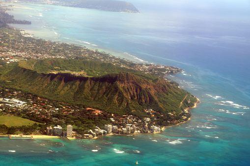 Aerial view of Diamond Head Crater, Kapiolani park, Black Point and Kahala on Oahu with wave braking against reef on nice day.