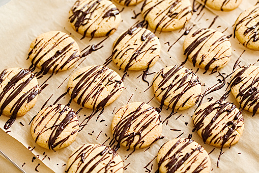 Butter orange cookies with dark chocolate drizzle glaze on a baking paper