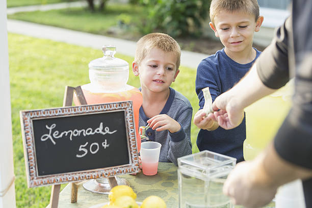 istock Boys with lemonade stand, taking payment from man 638960266