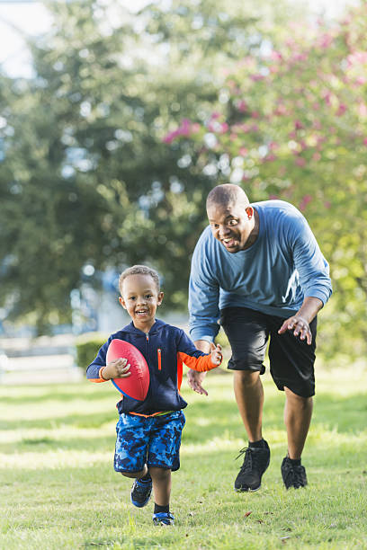 istock Little boy and father playing in the park with ball 638963544
