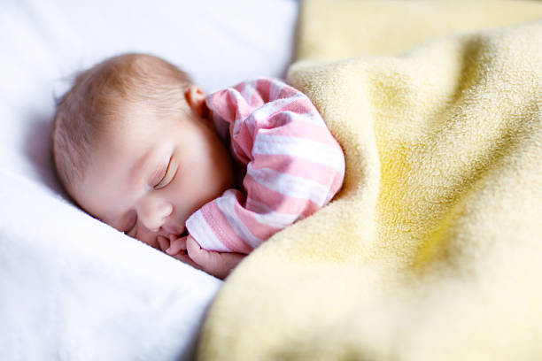 Portrait of cute adorable newborn baby girl sleeping Cute adorable newborn baby sleeping in white bed. New born child, little girl laying in bed. Family, new life, childhood, beginning concept. night hospital bed stock pictures, royalty-free photos & images