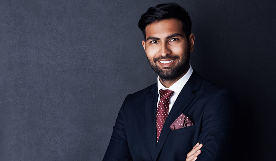 Studio shot of a confident young businessman posing against a gray background