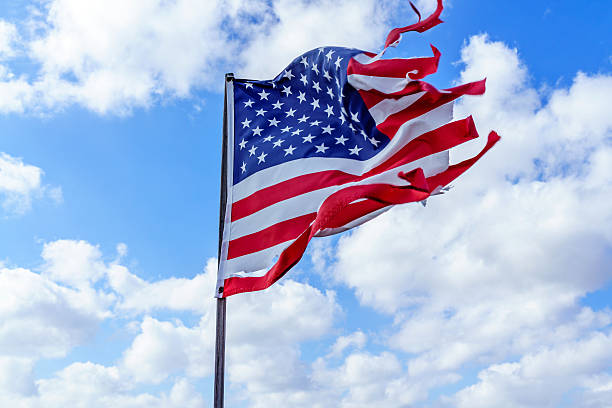 istock Tattered American flag flapping in blue sky 638984620