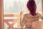 Woman sitting in a comfortable chair drinking coffee at home.