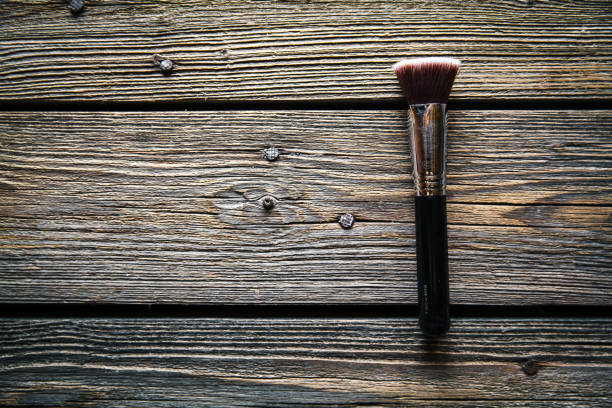 Makeup products arranged on a wooden and black surface, showing different brands and colors