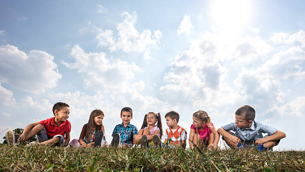Group of cute kids relaxing in grass and communicating.