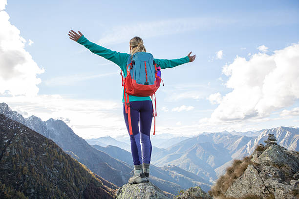 joven mujer caminando llega a la cima de la montaña, outstretches brazos - aspirations mountain hiking climbing fotografías e imágenes de stock