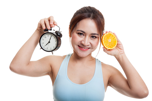 Beautiful Asian healthy girl with orange and clock  isolated on white background.