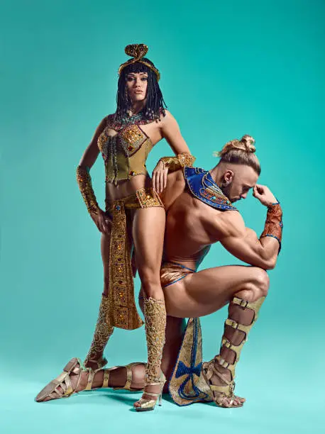 The man and woman in the images of Egyptian Pharaoh and Cleopatra on blue studio background