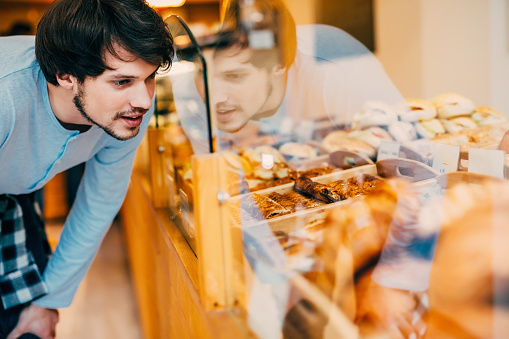 Young man choosing what to buy at the bakery.