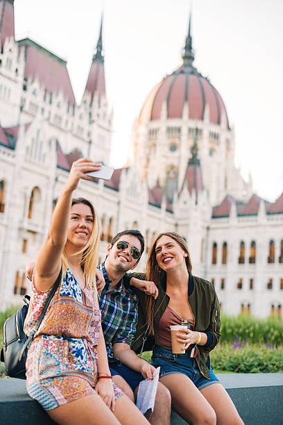 Couple or group of young friends sightseeing Budapest, Hungary, exploring its famous landmarks and having fun on sunny summer day. Images taken near Danube river bank in Budapest, near Lanchid (Chain Bridge) and parliament.
