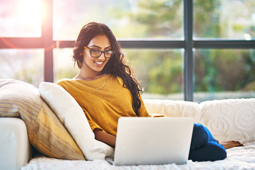 Shot of a relaxed young woman using a laptop on the sofa at home