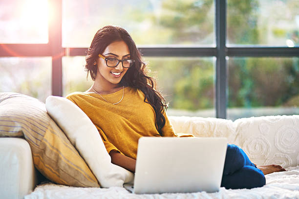 Relaxation doesn’t get any better than this Shot of a relaxed young woman using a laptop on the sofa at home indian ethnicity lifestyle stock pictures, royalty-free photos & images