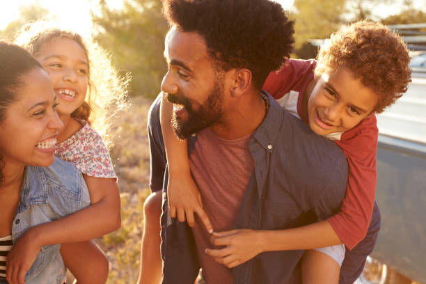 parents giving their kids piggybacks, waist up, close up - fun family couple happiness imagens e fotografias de stock