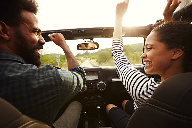 heureux couple conduisant dans leur voiture les bras en l’air - multi ethnic group flash photos et images de collection