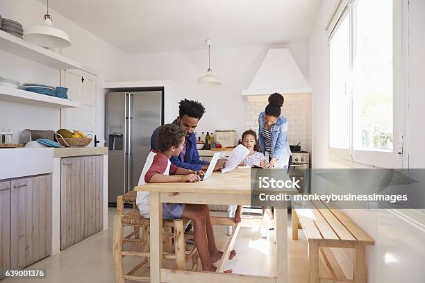 Mum And Dad Help Their Kids With Homework At Kitchen Stock Photo - Download Image Now