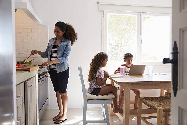 istock Mum cooking while kids work at kitchen table, from doorway 639001420