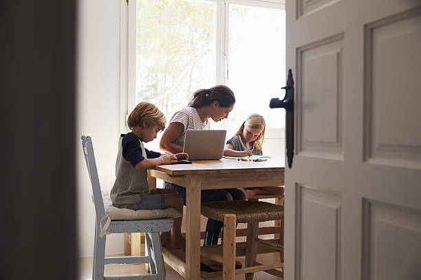 Mum and two kids working in kitchen, close up from Mum and two kids working in kitchen, close up from doorway homework table stock pictures, royalty-free photos & images
