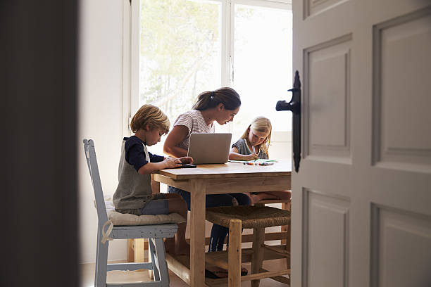 homework time images Mum and two kids working in kitchen, close up from Mum and two kids working in kitchen, close up from doorway homework table stock pictures, royalty-free photos & images