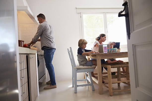 istock Dad cooking and mum with kids at kitchen table, low 639001430