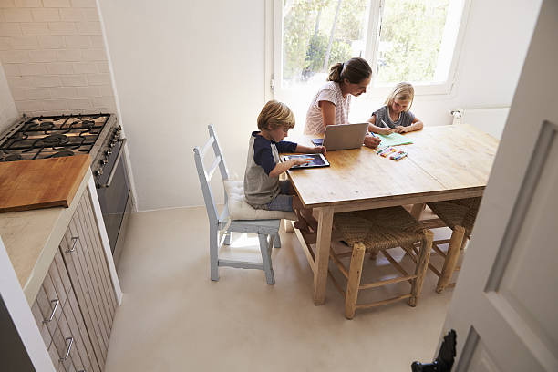 Mum and two kids working at kitchen table, elevated view