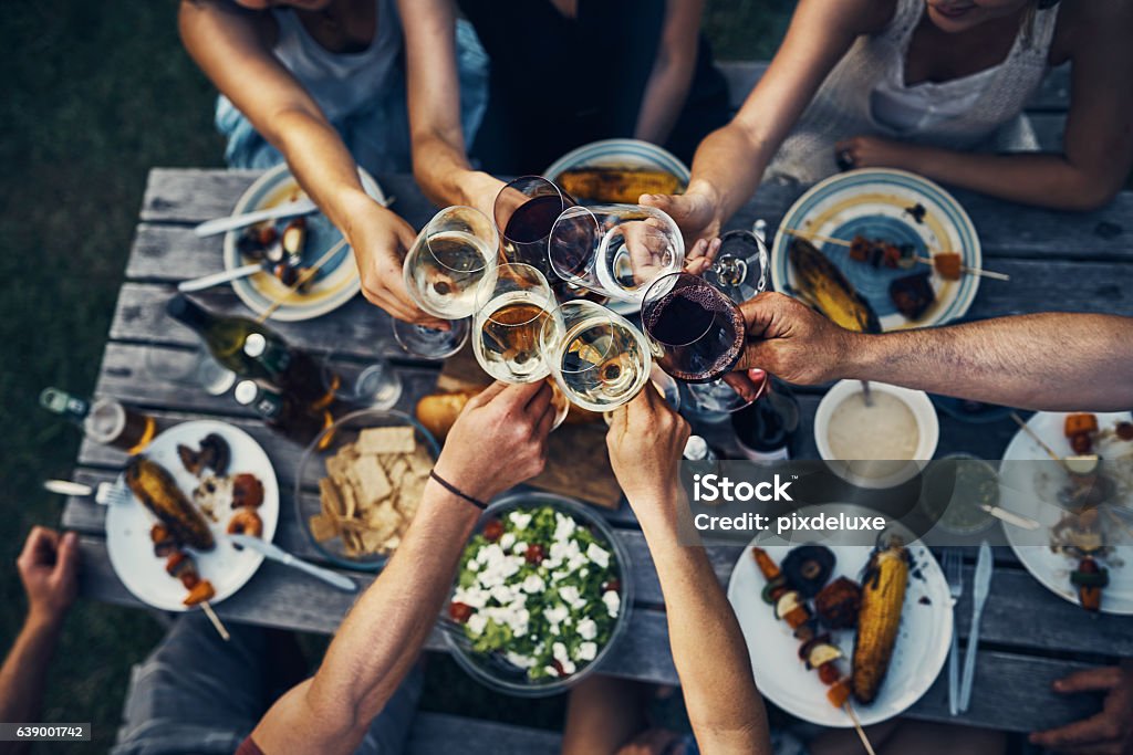 Food and wine brings people together Shot of a group of friends making a toast over dinner Wine Stock Photo
