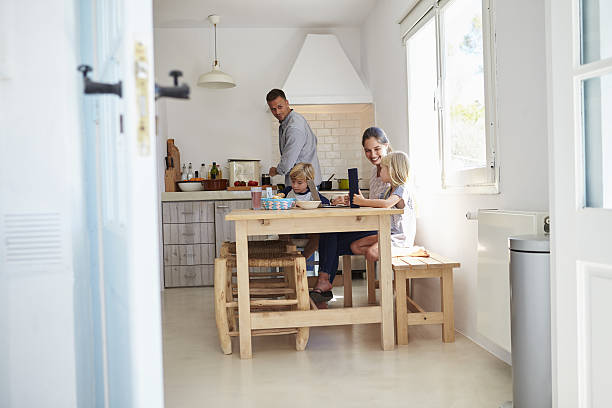 istock Kids at kitchen table with mum, dad cooks, view from 639001830