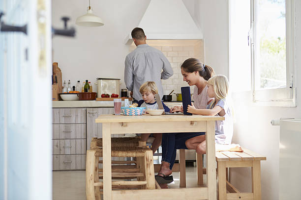 istock Kids at kitchen table with mum, dad cooks, view from 639001842