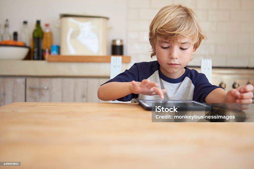 Niño usando la tableta en la mesa de la cocina, vista frontal - Foto de stock de Niño libre de derechos