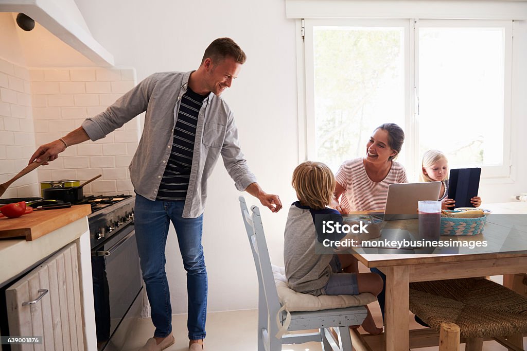 Dad cooking turns to mum with kids at the kitchen Dad cooking turns to mum with kids at the kitchen table Cooking Stock Photo