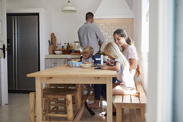 istock Kids do homework at kitchen table with mum while dad 639001888