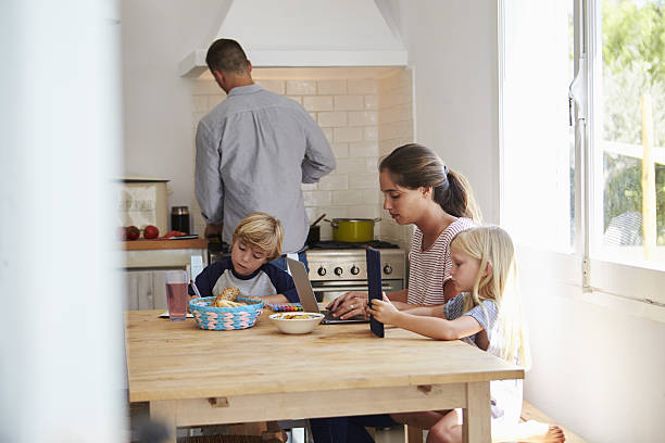 istock Kids and mum at table, dad cooking, three quarter length 639001902