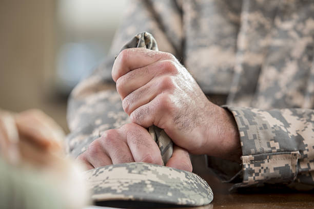 Close up of soldier's hands holding hat in counseling session Caucasian male veteran squeezes camouflage uniform hat during counseling session. Close up is of the man holding the hat. post traumatic stress disorder photos stock pictures, royalty-free photos & images