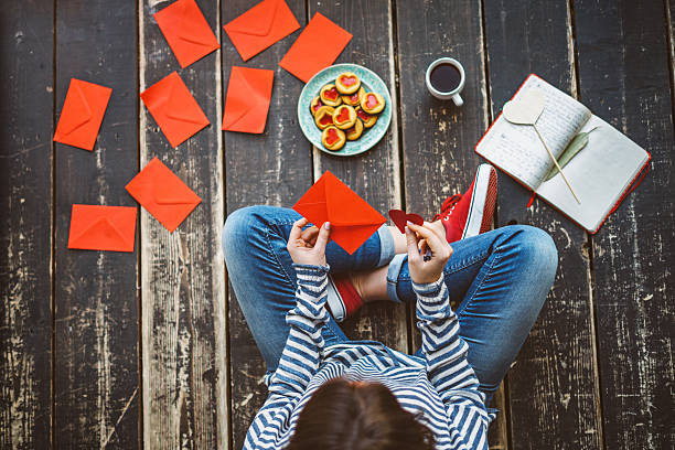 istock Young woman writing a valentine card - top view 639020010
